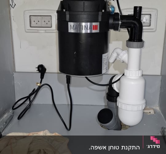 מתקן טוחן אשפה מותקן מתחת לכיור עם צנרת מחוברת